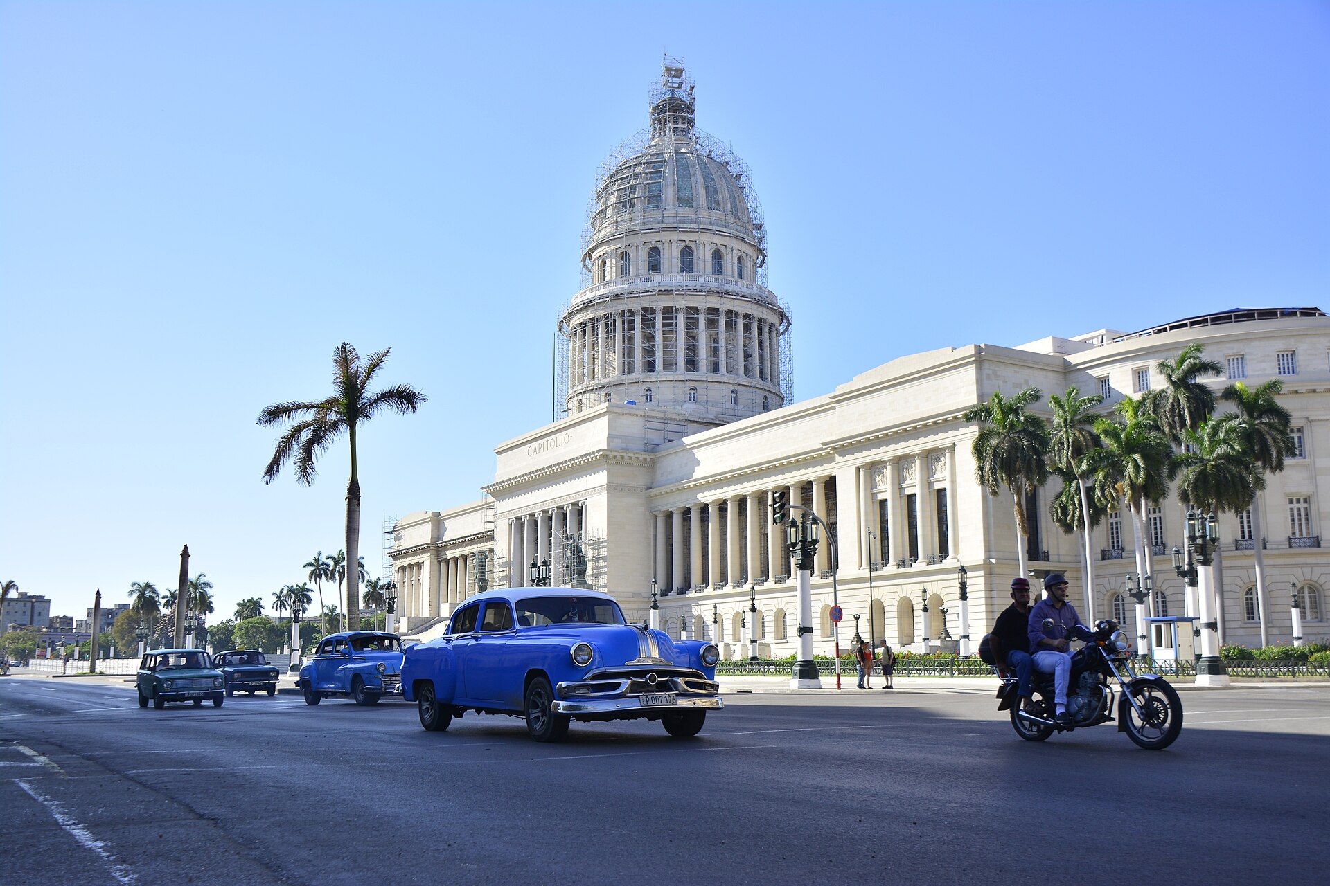 Das Capitolio in Havanna mit Palmen und einem blauen Oldtimer im Vordergrund, Kuba